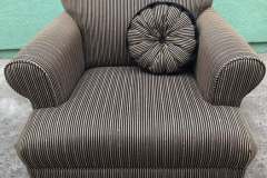 Brown pinstripe club chair with round black accent pillow