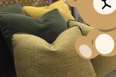 Stacked green and yellow throw pillows with bear graphic overlay