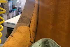 Close-up of deteriorated orange foam on vintage sofa frame in workshop