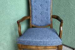Blue tufted dining armchair with carved wood frame