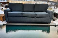 Dark teal three-cushion sofa photographed outdoors in snow