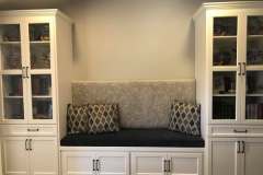 Built-in reading nook with cushion and patterned pillows between bookcases