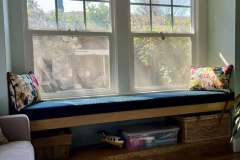Blue window seat cushion with floral throw pillows in client home