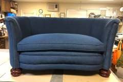 Navy blue rolled-arm loveseat with cherry bun feet in workshop