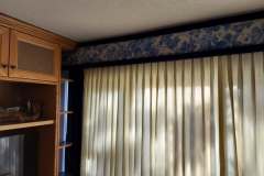 Blue floral valance with cream drapes over sliding door in living room