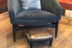 Gray barrel chair with metallic gold ottoman in client showroom