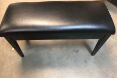 Black faux-leather piano bench seat in workshop