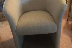 Light blue boucle barrel tub chair by fireplace
