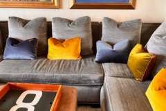 Gray sectional with colorful velvet pillows and tropical art