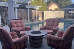 Set of four pink tufted outdoor patio chairs around fire pit by pool